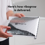 ribogrow hair booster tonic packaging shown being held in protective padded shipping envelope, featuring ribogrow branding and secure packaging designed to protect the glass bottle during delivery and ensure safe arrival to the customer.