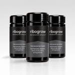 Drei schwarze ribogrow® Hair Booster Capsules Dosen mit glänzenden Schraubdeckeln und grau-schwarzen Etiketten. Die Nahrungsergänzungsmittel enthalten einen Phyto-Nährstoff-Komplex mit Sägepalme, Vitaminen, Aminosäuren, EGCG und Polyphenolen. Die Dosen sind versetzt vor einem hellgrauen Hintergrund auf einer spiegelnden weißen Oberfläche angeordnet.