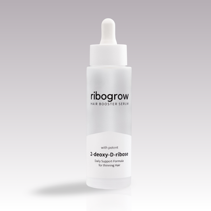 Einzelne Flasche ribogrow Hair Booster Serum aus mattem Glas mit weißem Pipettenverschluss, auf hellem, sanft verlaufendem Hintergrund stehend.