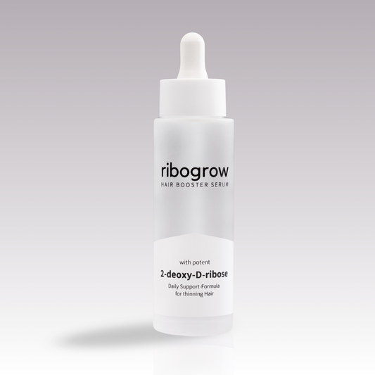 Einzelne Flasche ribogrow Hair Booster Serum aus mattem Glas mit weißem Pipettenverschluss, auf hellem, sanft verlaufendem Hintergrund stehend.