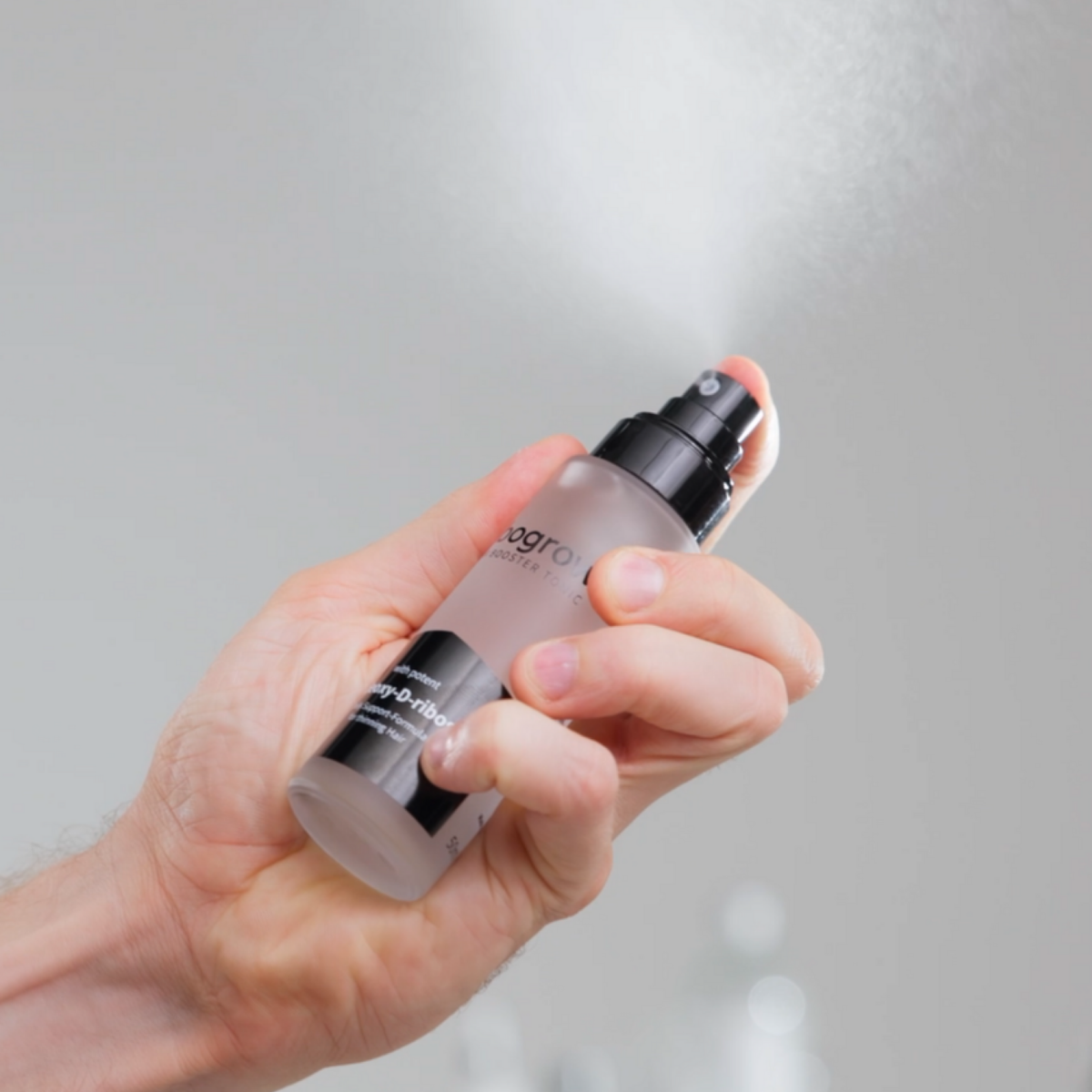 Zeigt der super feinen Sprhnebel des ribogrow Hair Booster Tonics in einer Männerhand