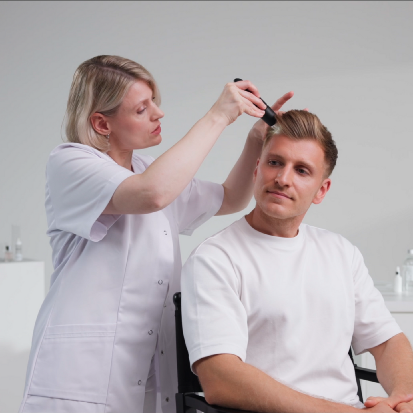 Zeigt eine Dermatologin wie sie einem männlichen Patienten mit einem Trichoscan nach der Anwendung dichteres Haar attestiert
